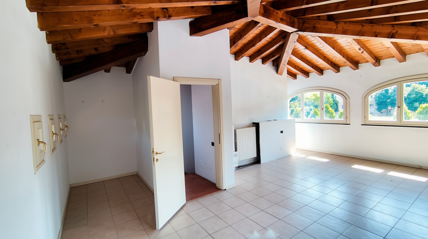Mansarda con travi in legno e finestre ad arco