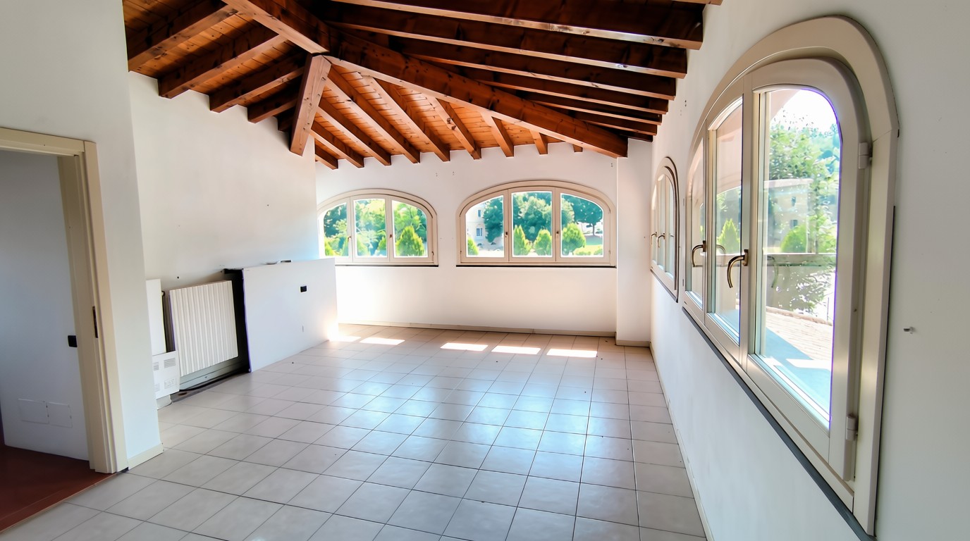 Ampia mansarda con tetto in legno e finestre ad arco